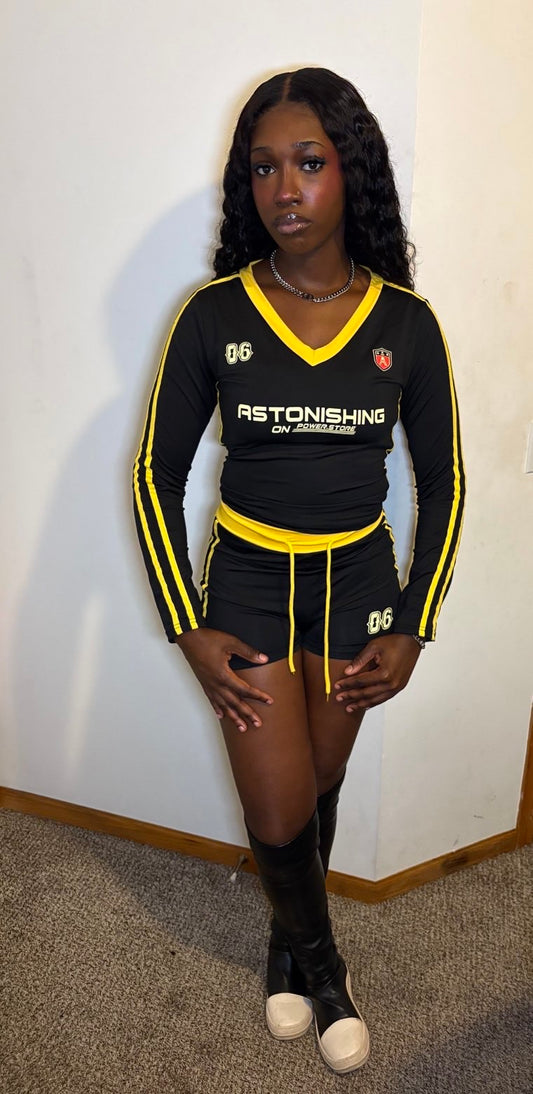 Person wearing a black and yellow sports outfit with visible branding against a plain wall.